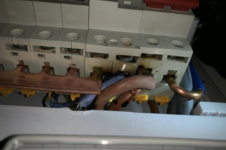 Inside of a consumer unit showing scorched, damaged neutral bar — typical emergency call-out find